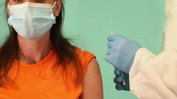 Il medico inietta il vaccino con siringa contro il covid19 coronavirus. Sfondo ciano — Video Stock