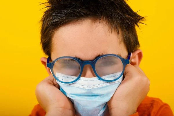 Дитина з туманною лінзою через маску для обличчя від коронавірусу. жовтий фон — стокове фото