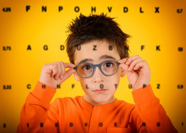 Niño intenta gafas nuevas para ver mejor. fondo amarillo —  Fotos de Stock