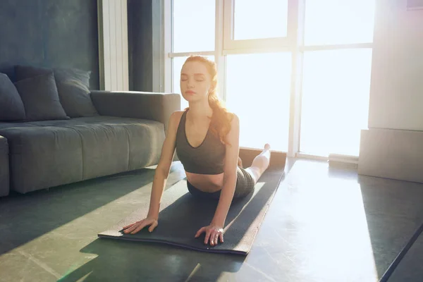 Young girl does gym exercises during sunrise. She is at home due to coronavirus codiv-19 quarantine — Stock Photo, Image