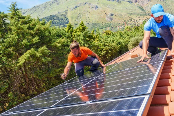 Workers assemble energy system with solar panel for electricity and hot water