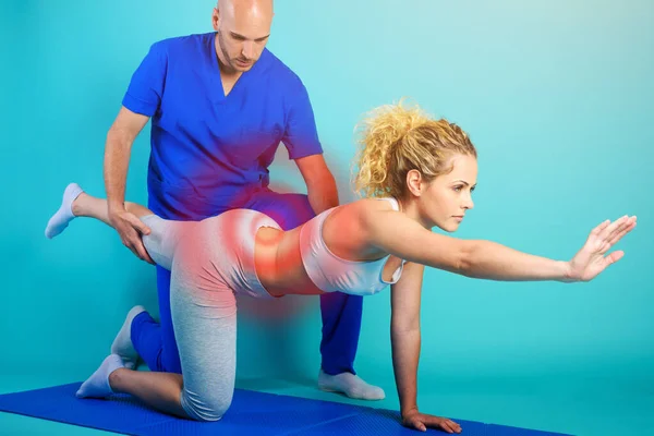 Girl performs exercises with a physiotherapist. Cyan background — Stock Photo, Image