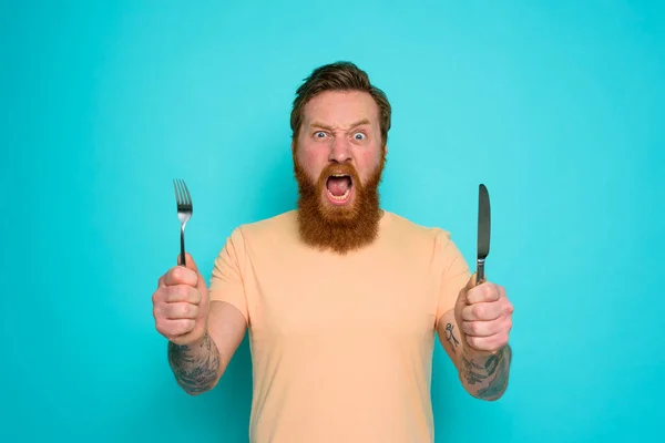 Uomo affamato con tatuaggi è pronto da mangiare con le posate in mano — Foto Stock
