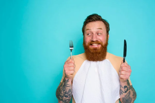 Uomo felice con tatuaggi è pronto da mangiare con le posate in mano — Foto Stock