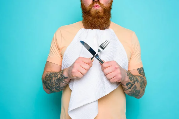 Mężczyzna z tatuażami jest gotowy do jedzenia ze sztućcami w ręku — Zdjęcie stockowe