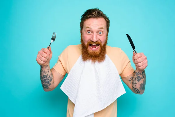 Πεινασμένος άνθρωπος με τατουάζ είναι έτοιμος να φάει με μαχαιροπήρουνα στο χέρι — Φωτογραφία Αρχείου