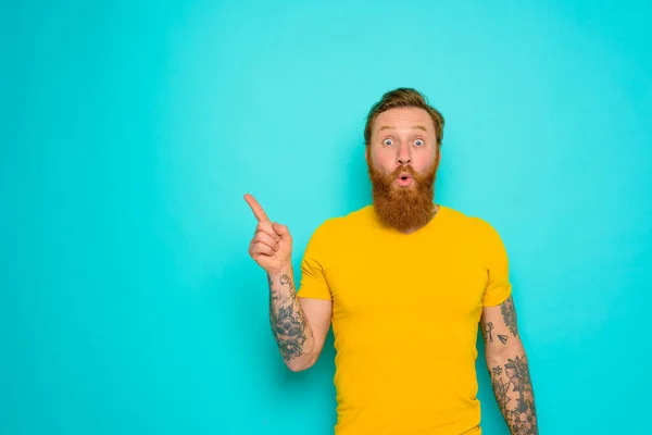 Man with yellow t-shirt and beard is shocked about something — Stock Photo, Image