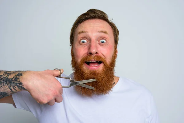 Nieszczęśliwy człowiek z nożyczkami nie chce obcinać brody. — Zdjęcie stockowe
