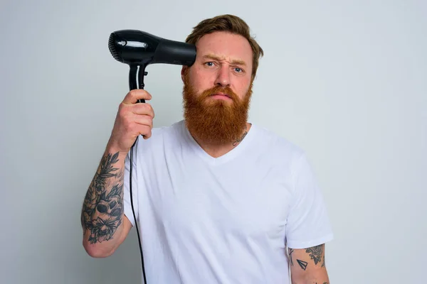 Unhappy man with beard play with hair dryeras a handgun — Stock Photo, Image