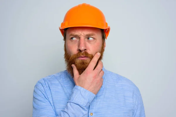Izolovaný pochybovačný architekt s vousy a oranžovou přilbou — Stock fotografie