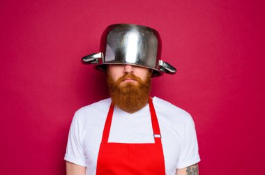 unhappy chef with beard and red apron plays with pot