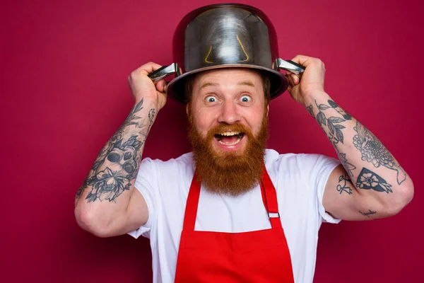 Szczęśliwy szef kuchni z brodą i czerwonym fartuchem bawi się trawką — Zdjęcie stockowe