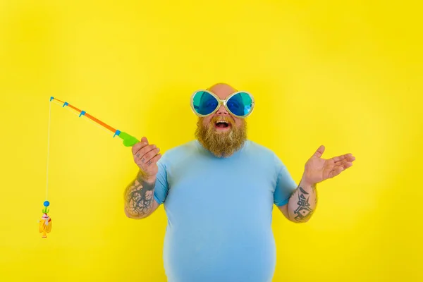 Grasso uomo con barba e occhiali da sole divertirsi con la canna da pesca — Foto Stock