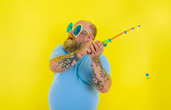 Hombre gordo con barba y gafas de sol divertirse con la caña de pescar — Foto de Stock