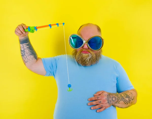 Fat man with beard and sunglasses is unhappy with the fishing rod — Stock Photo, Image