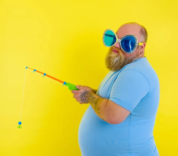 Grasso uomo con barba e occhiali da sole è infelice con la canna da pesca — Foto Stock