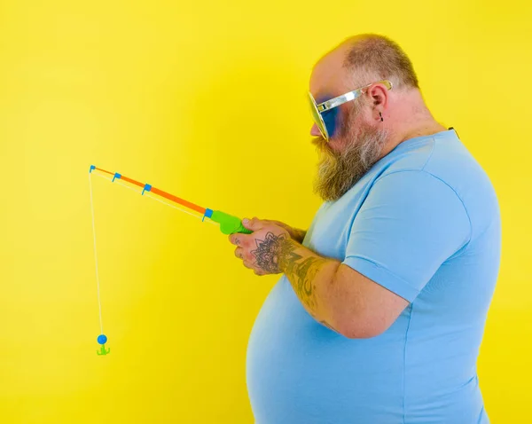 Fat man with beard and sunglasses is unhappy with the fishing rod — Stock Photo, Image
