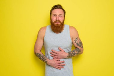 Sakallı ve dövmeli ızdırap çeken adamın midesi ağrıyor.