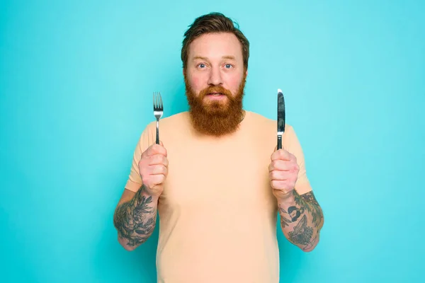 L'uomo con i tatuaggi è pronto da mangiare con le posate in mano — Foto Stock