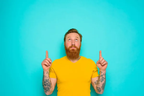 Uomo con t-shirt gialla e barba è sorpreso da qualcosa — Foto Stock