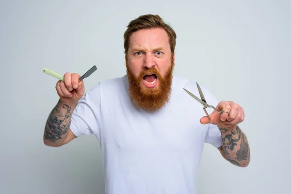 Agresywny mężczyzna z nożyczkami i ostrzem jest gotowy obciąć brodę. — Zdjęcie stockowe