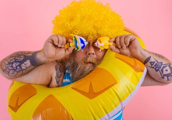 Grasso uomo con parrucca in testa è pronto a nuotare con un salvagente ciambella — Foto Stock