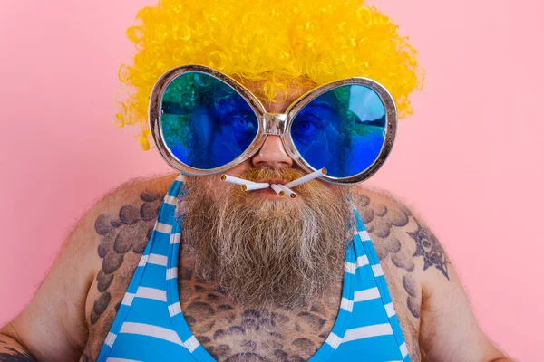 Grasso uomo serio con barba e parrucca fuma sigarette — Foto Stock