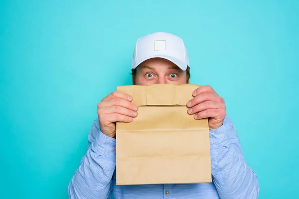 Entrega homem esconde seu rosto com um pacote de alimentos — Fotografia de Stock