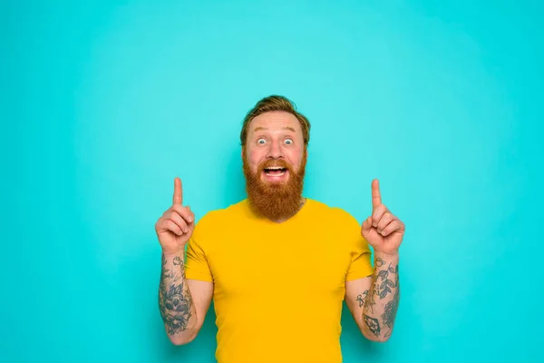 Homme avec t-shirt jaune et barbe est choqué par quelque chose — Photo