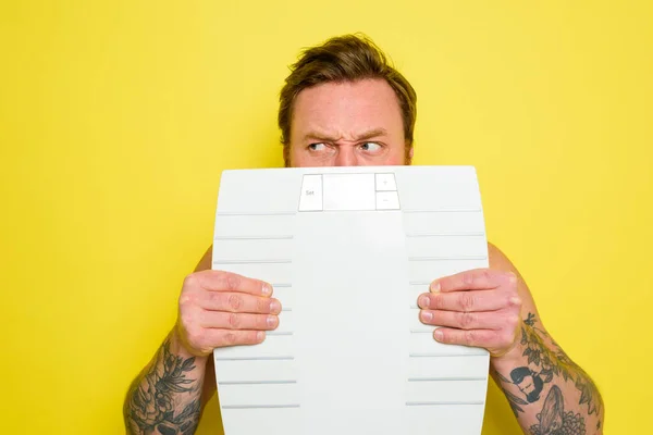 Dubious man with beard and tattoos is hidden behind the scales — Stock Photo, Image