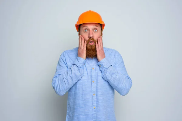 Isolato architetto stupito con barba e casco arancione — Foto Stock