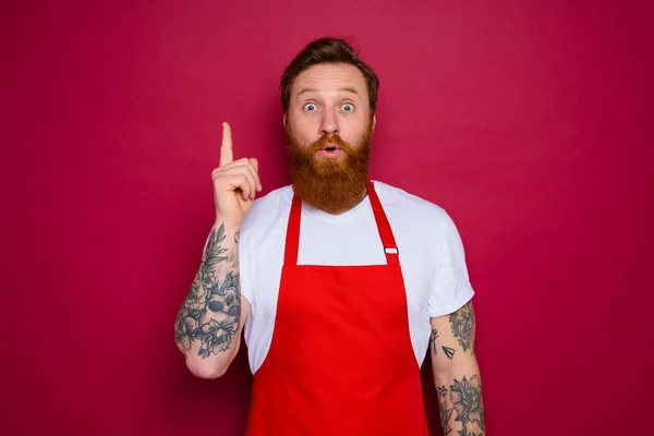Stupito chef isolato con barba e grembiule rosso — Foto Stock
