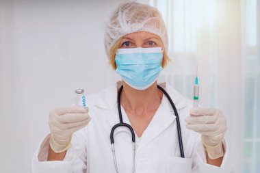Maskeli ve şırıngalı doktor Covid-19 'a karşı aşı uygulamaya hazır.