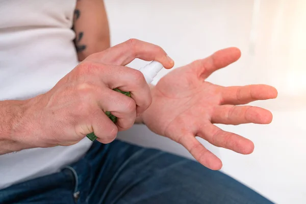 De mens reinigt de hand met een spray desinfecterend middel tegen covid-19 — Stockfoto