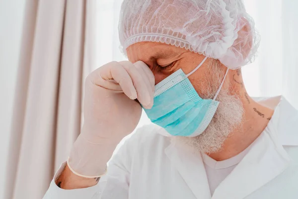 Доктор в маске и защитнике лица устал от пандемии вируса ковид-19. — стоковое фото