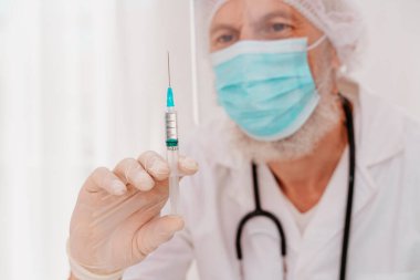 Maskeli ve şırıngalı doktor Covid 19 'a karşı aşı uygulamaya hazır.
