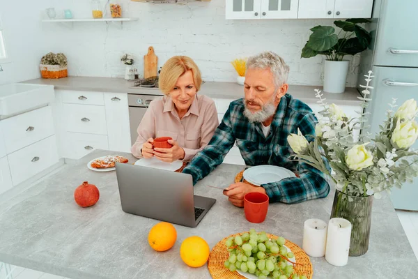 दोन घरी नाश्ता करतात आणि लॅपटॉपमधून काहीतरी पाहतात — स्टॉक फोटो, इमेज