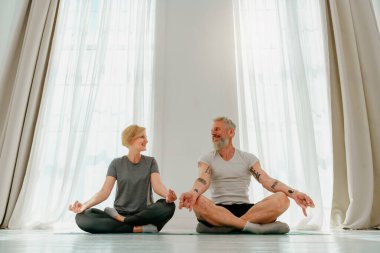 Karı koca evde yoga egzersizi yapıyor.