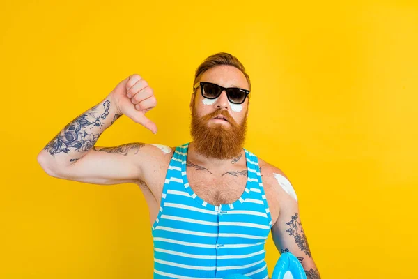 Man with tattoos and swimsuit puts on sunscreen — Stock Photo, Image