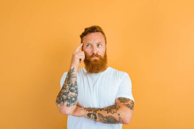 Thoughtful man with beard, tattoo and white t-shirt