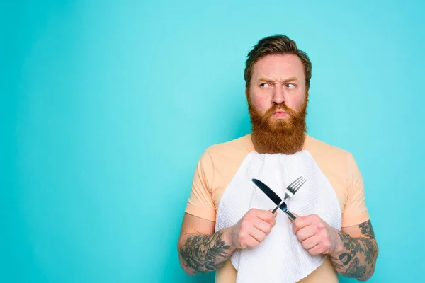 L'uomo con i tatuaggi è pronto a mangiare con le posate in mano con qualche dubbio — Foto Stock