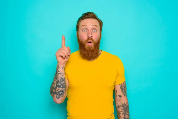 Homme avec t-shirt jaune et barbe est surpris de quelque chose — Photo