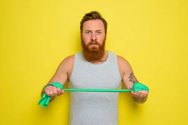 Uomo con barba e tatuaggi si allena con un elastico — Foto Stock