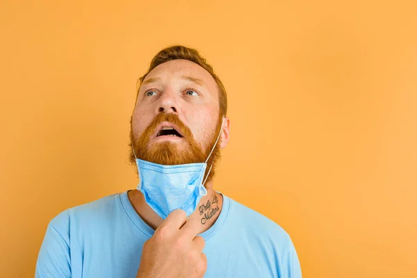 Muž s vousy a tetováním odstraňuje masku pro covid-19 — Stock fotografie