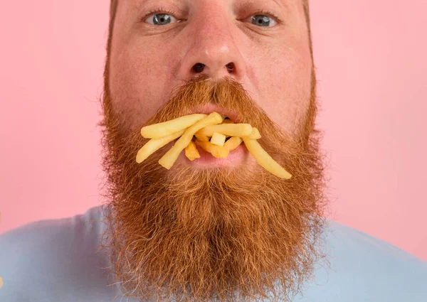 Uomo affamato con barba e tatuaggi mangia patate fritte — Foto Stock