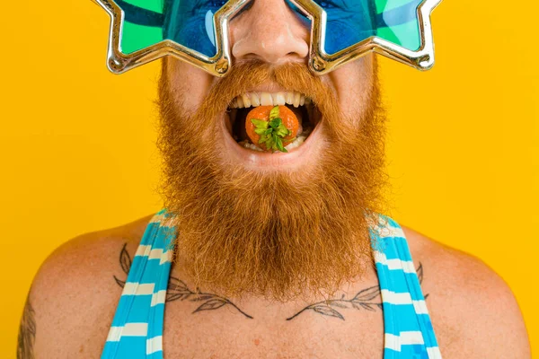 Uomo con barba e occhiali da sole mangia una fragola — Foto Stock