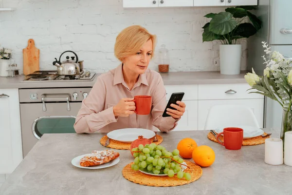 Frau frühstückt zu Hause mit Obst, Kuchen und Kaffee — Stockfoto