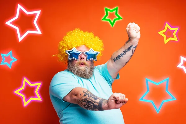 Толстяк с бородой, татуировками и солнцезащитными очками танцует на дискотеке — стоковое фото