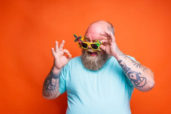 Tłusty szczęśliwy człowiek z brodą, tatuażami i okularami jest gotowy na lato — Zdjęcie stockowe