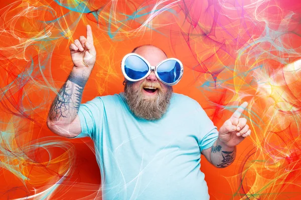 Gros homme heureux avec barbe, tatouages et lunettes de soleil danse musique — Photo